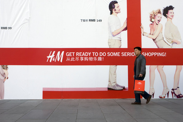 A shopper walks past an advertisement for an upcoming Hennes & Mauritz (H&M) AB store in Beijing, China. Photographer: Nelson Ching/Bloomberg News